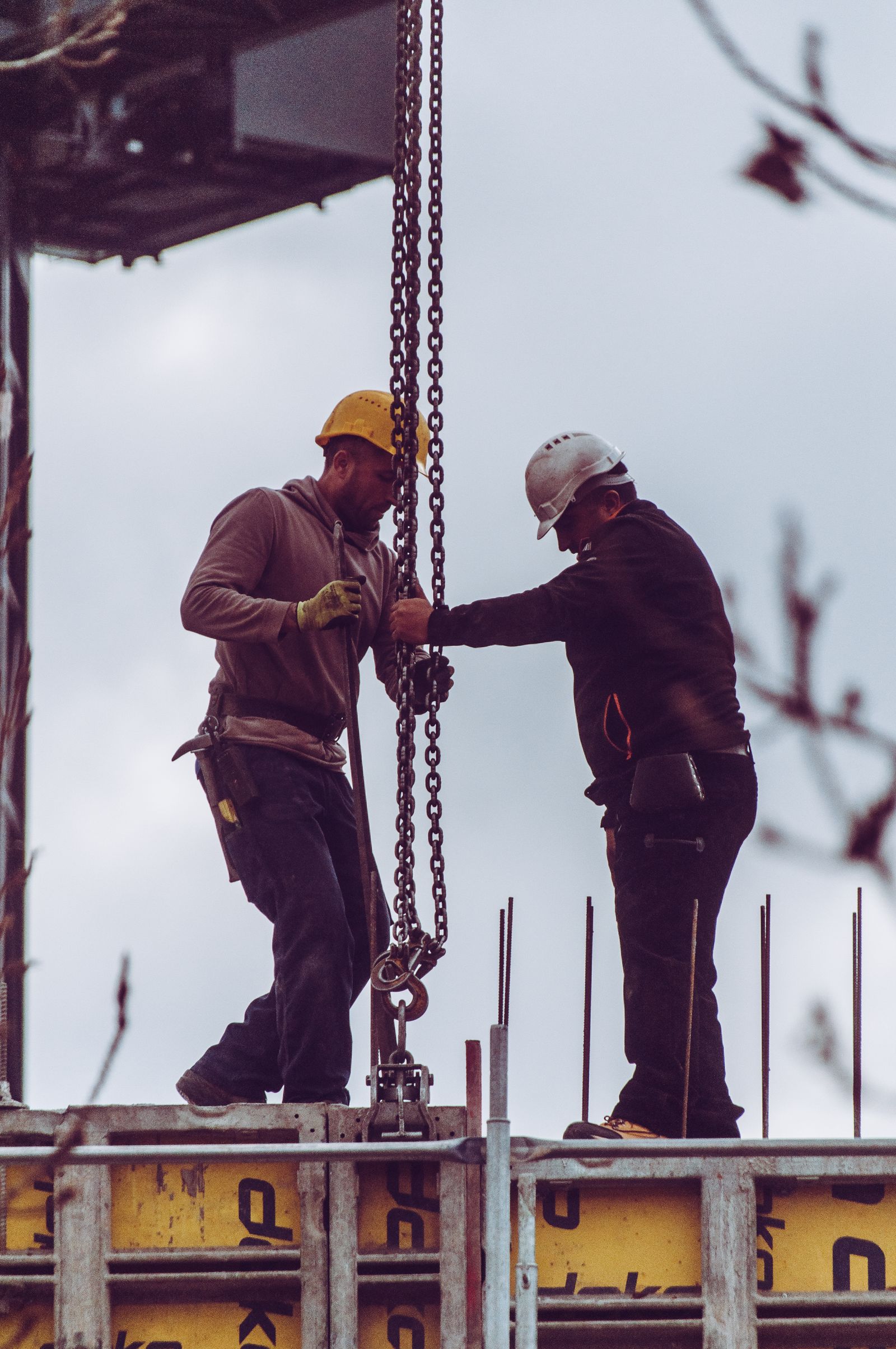 Workers operating a chain hoist on a construction site