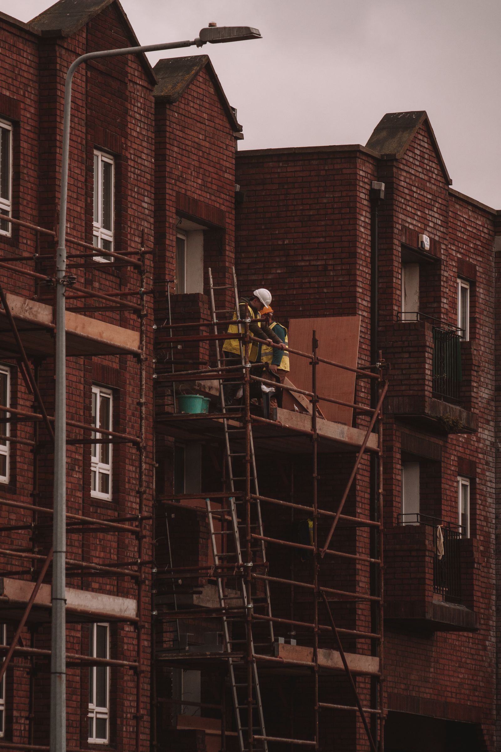 Builders working on scaffolding at a brick residential building